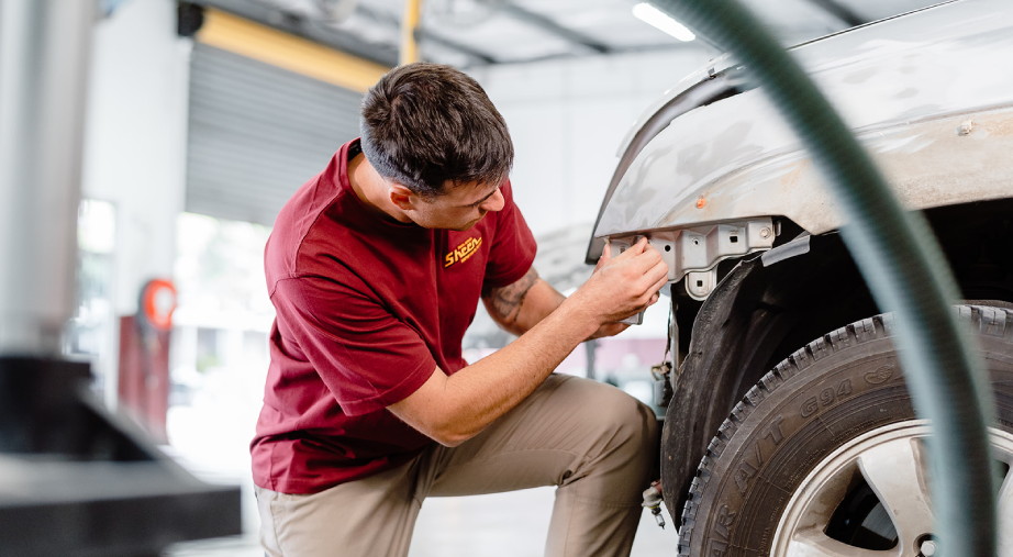Sheen technician inspecting front panel damage during smash repair assessment.