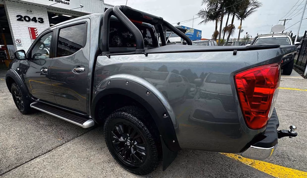 Rear-side view of a grey Nissan Navara ute after repair, with the tray and rear panels fully restored, clean body lines, and no visible damage.