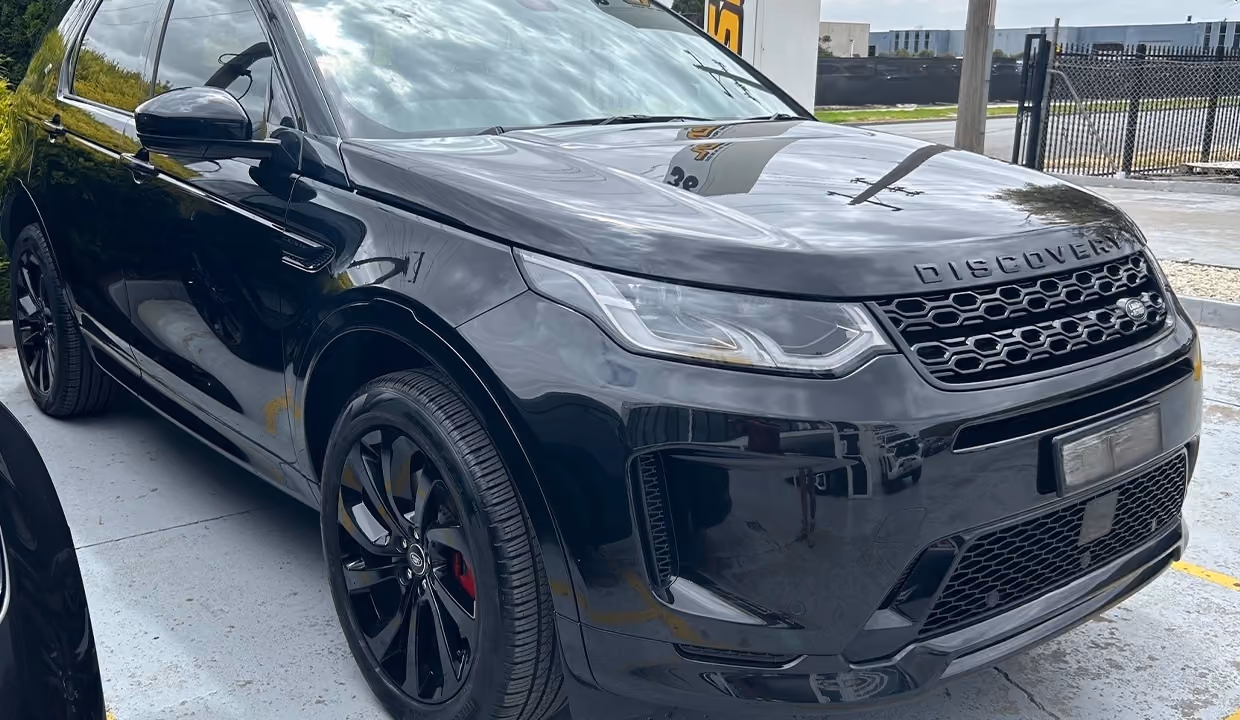 Front-side view of a black Land Rover Discovery after repair, with a smooth, restored wheel arch and front panel, finished to a clean, like-new condition.