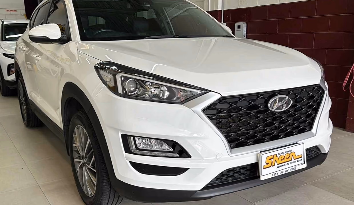 Front-side view of a white Hyundai Tucson after repair, with a smooth, restored bumper and clean, factory-like finish.