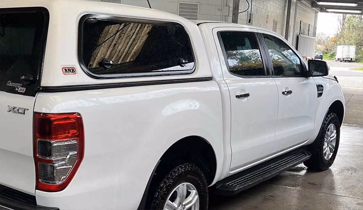 Rear-side view of a white Ford Ranger ute after repair, with a smooth, restored wheel arch and tray side panel in clean condition.
