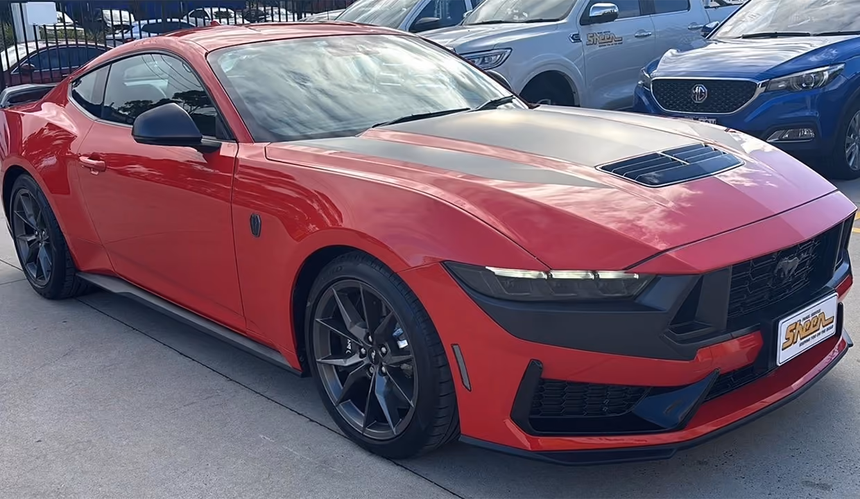 Front three-quarter view of a red Ford Mustang after repair, showcasing a fully restored front end with clean panel alignment, smooth body lines, and a flawless high-gloss finish.