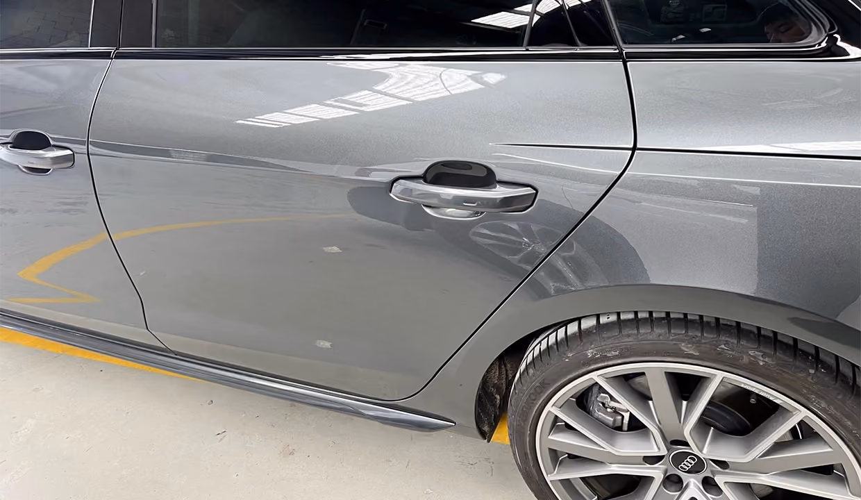 Close-up side view of an Audi A4 after paintless dent removal, featuring a smooth, restored door panel with flawless reflections and no visible damage.