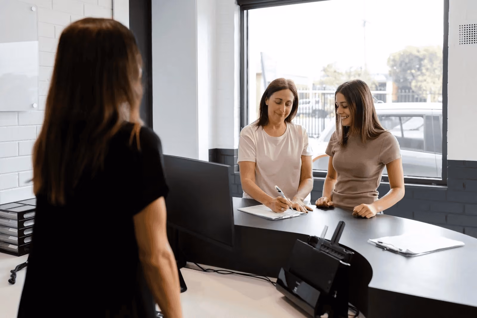 Customers completing paperwork at a Sheen reception desk before collecting their repaired vehicle.
