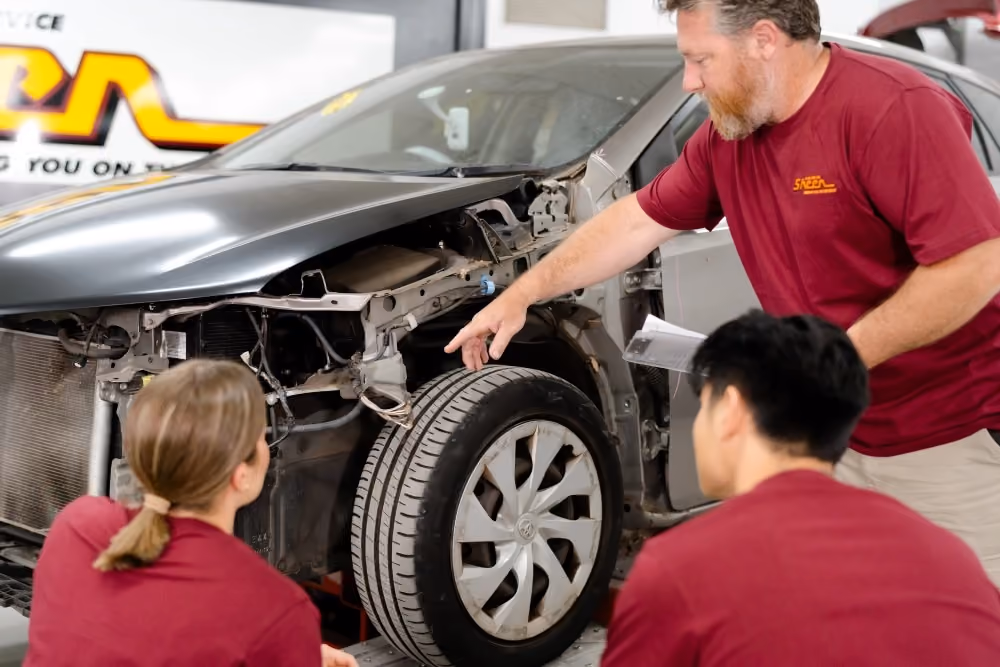 Sheen technician explaining vehicle damage and repair requirements to workshop team members.