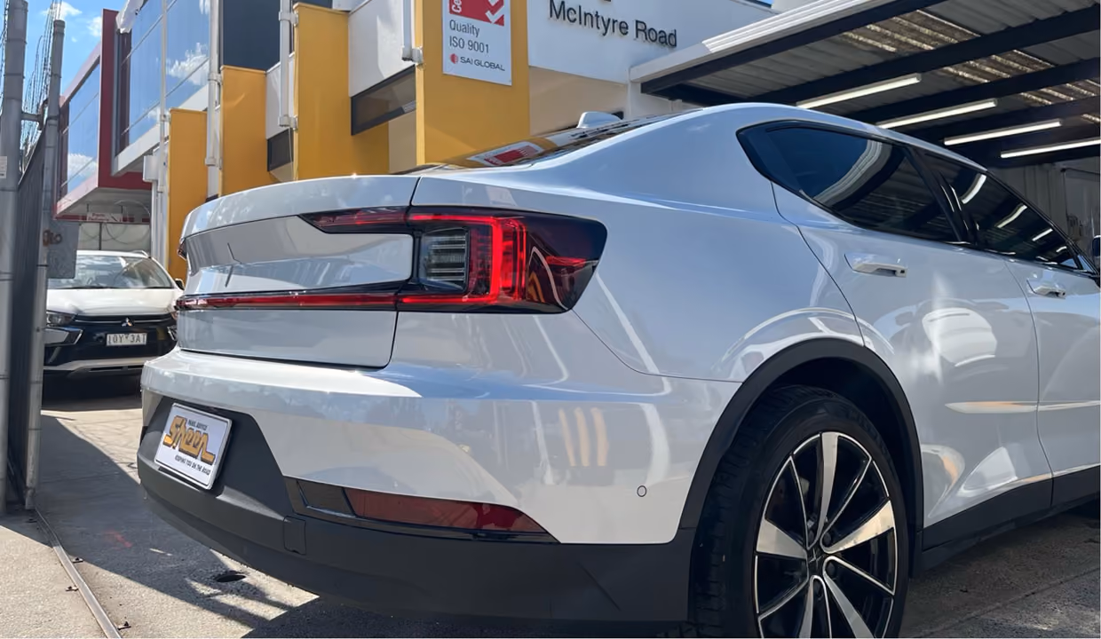 Repaired white Polestar 2 electric vehicle outside Sheen Panel Service workshop.