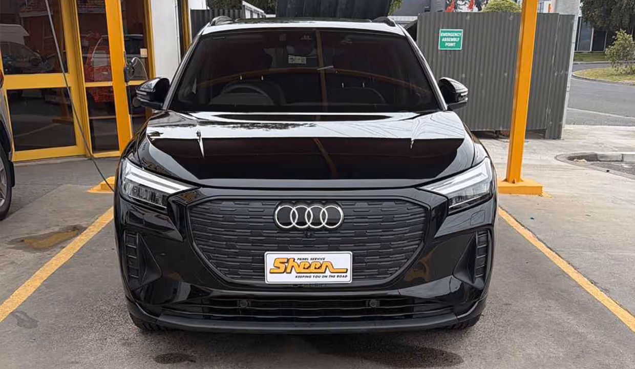 Repaired black Audi Q4 e-tron electric vehicle after front-end collision repairs.