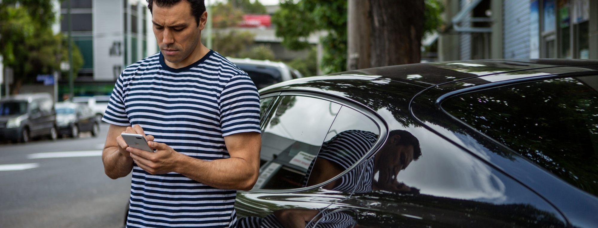 Man checking his phone beside his car after a minor accident.