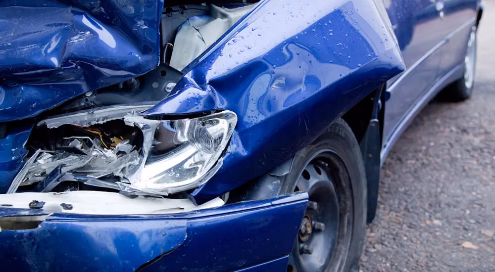 Customer photographing rear bumper damage on a red car with a tablet at the crash site to record details for a car insurance claim and smash repair.