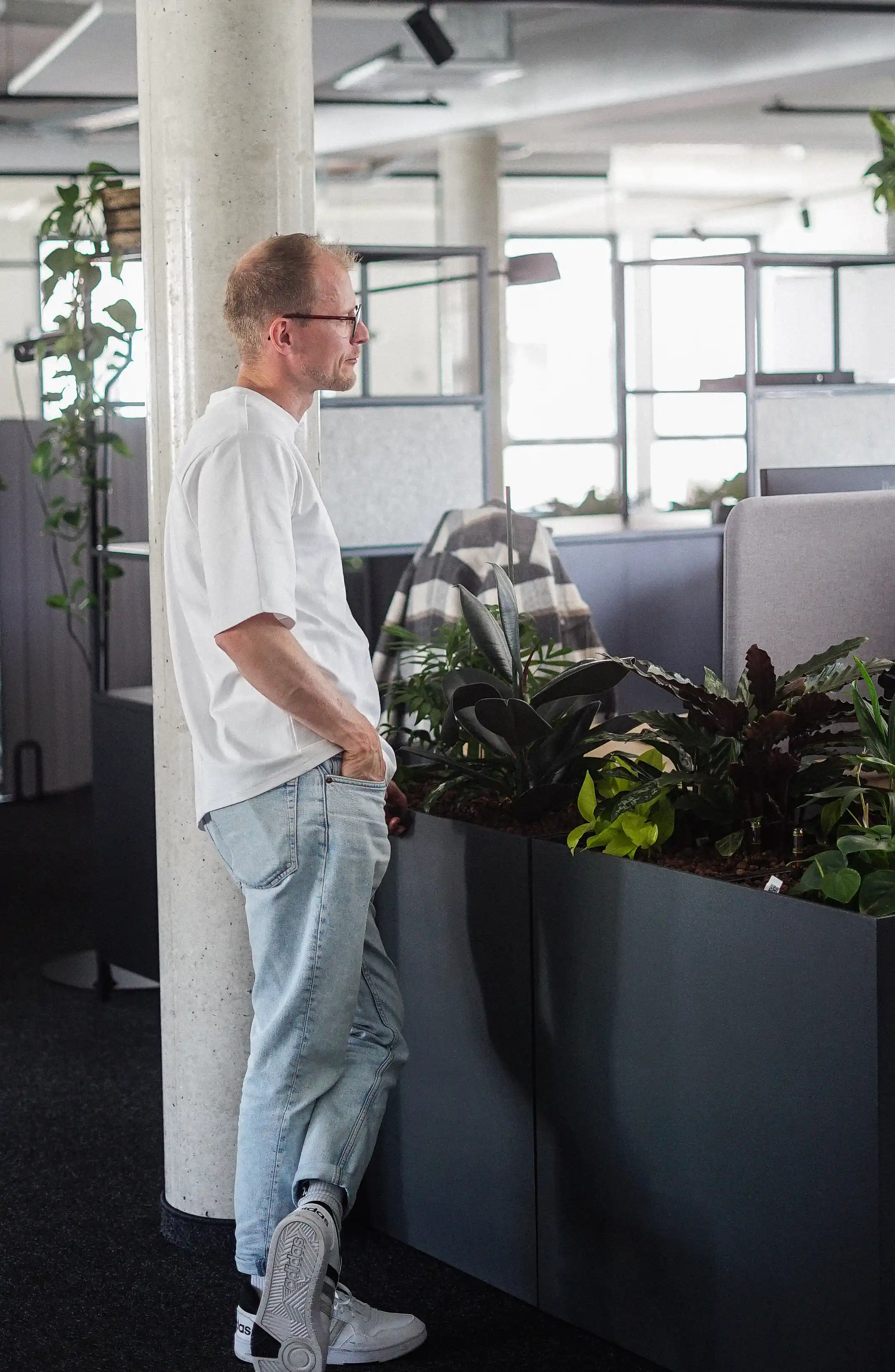 One man leaning against a column in an office.