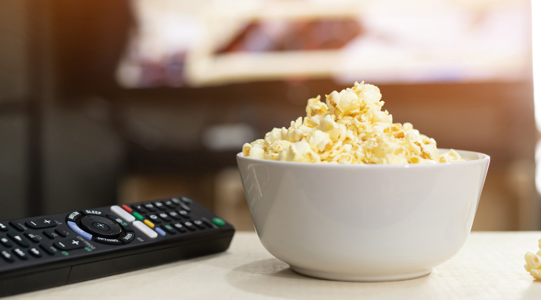 A TV remote and a bowl of popcorn