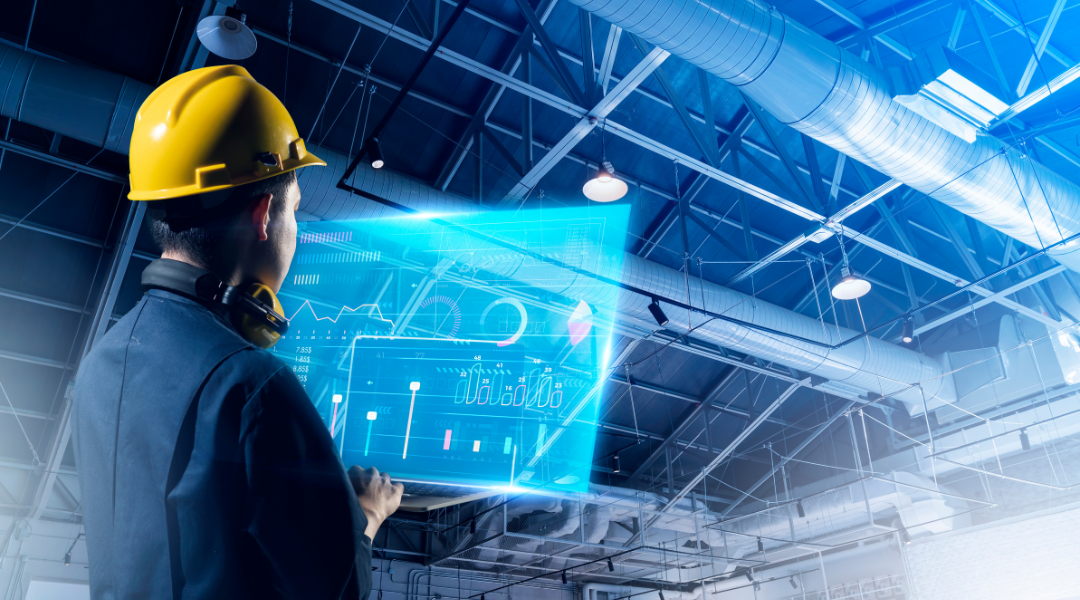 An architect with a hard hat on looking at a hologram at his computer in a warehouse