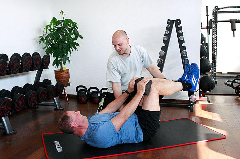 Physiotherapeut macht Bodenübungen mit Patient