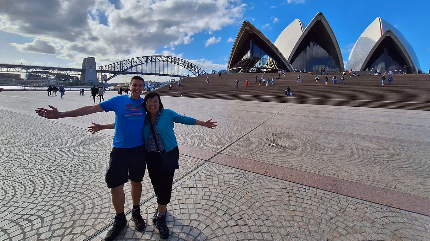 Two Wealth of Advice clients enjoying their retirement in front of a landmark in Sydney during their family holiday to Australia.