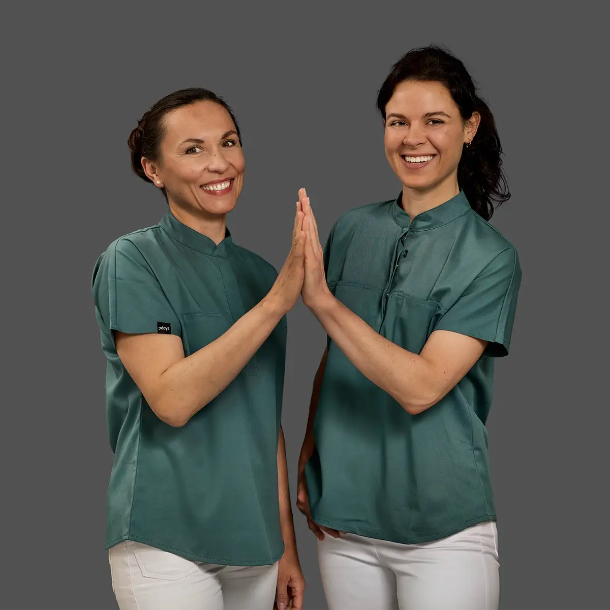 Zwei lächelnde Frauen in grünen Hemden geben sich gegenseitig einen Highfive: Dr. Irina Heeren und Dr. Vivien Arbter