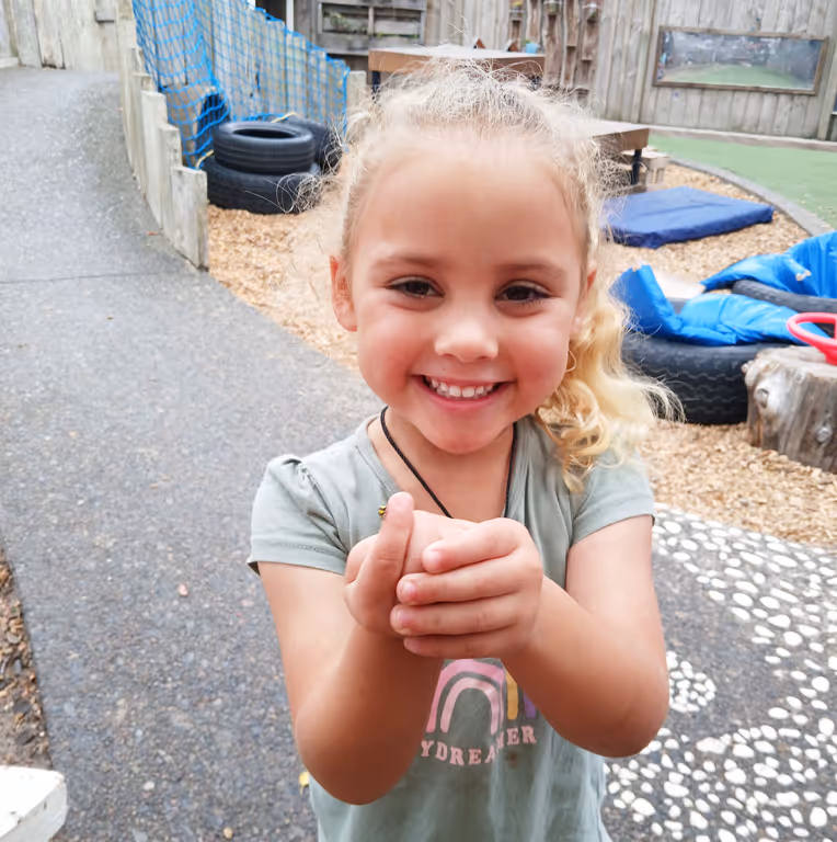 Preschooler holding up a wee bug on her finger
