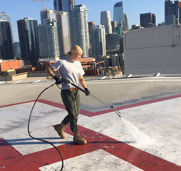 Technician pressure washing concrete surface.