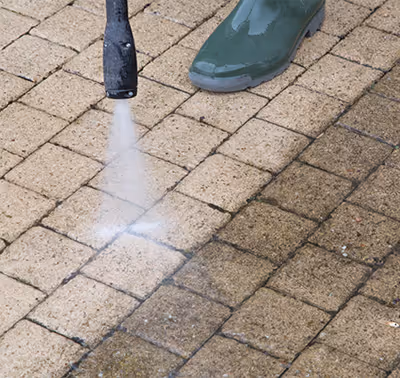 Technician pressure washing paver/brick surface.