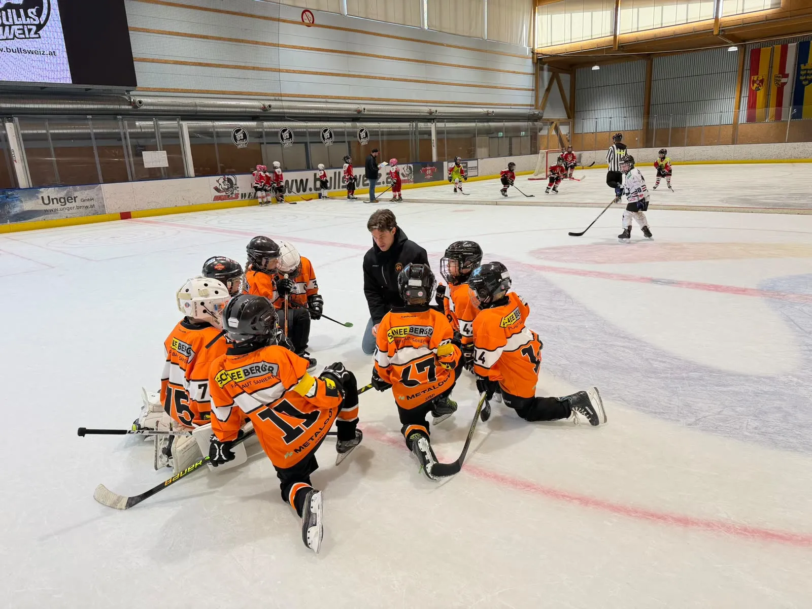 Orange gekleidete Spieler sitzen in einer Spielpause am Eis