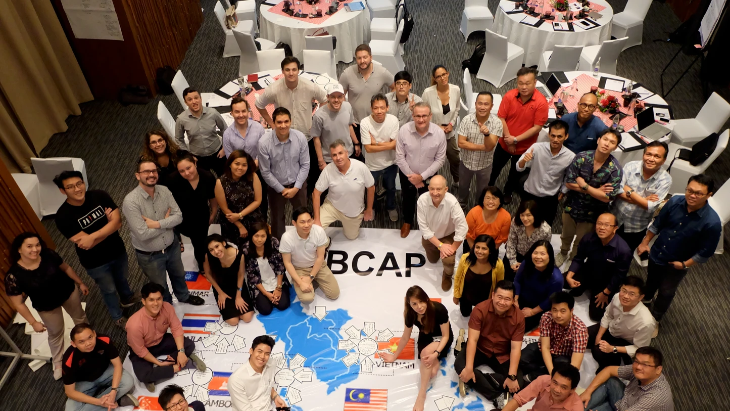 Brand Connect Asia Pacific team gathered around a floor map of the region at their TIPS workshop
