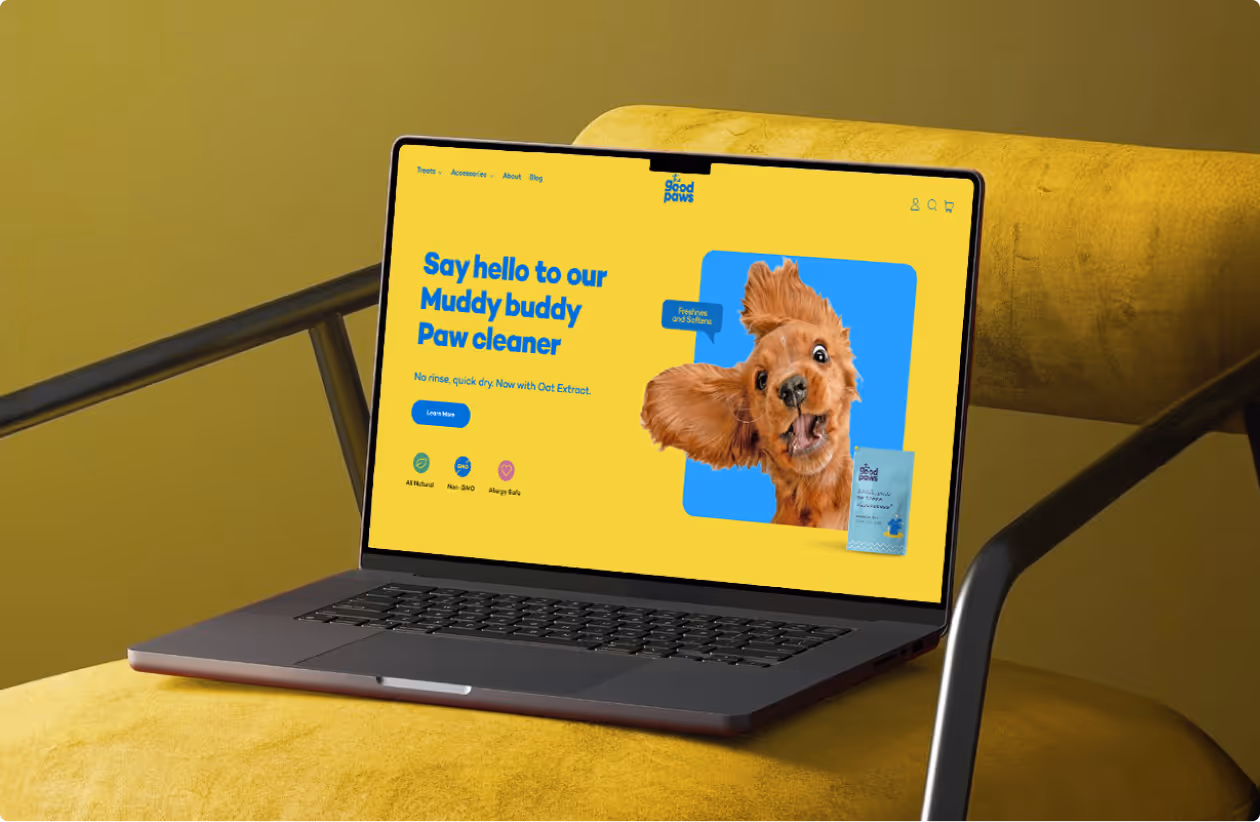 Laptop displaying a yellow webpage advertising a Muddy buddy Paw cleaner with a playful dog image and product package, placed on a mustard yellow chair.