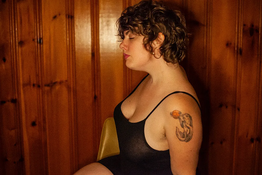 Profile image of Jill wearing a black tank top with her eyes open against a wood paneled wall.