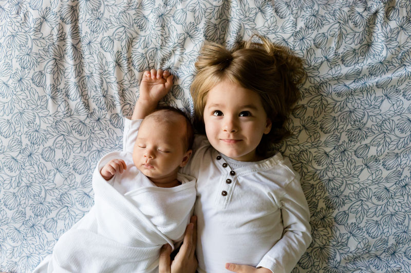 Baby and toddler laying on a bad