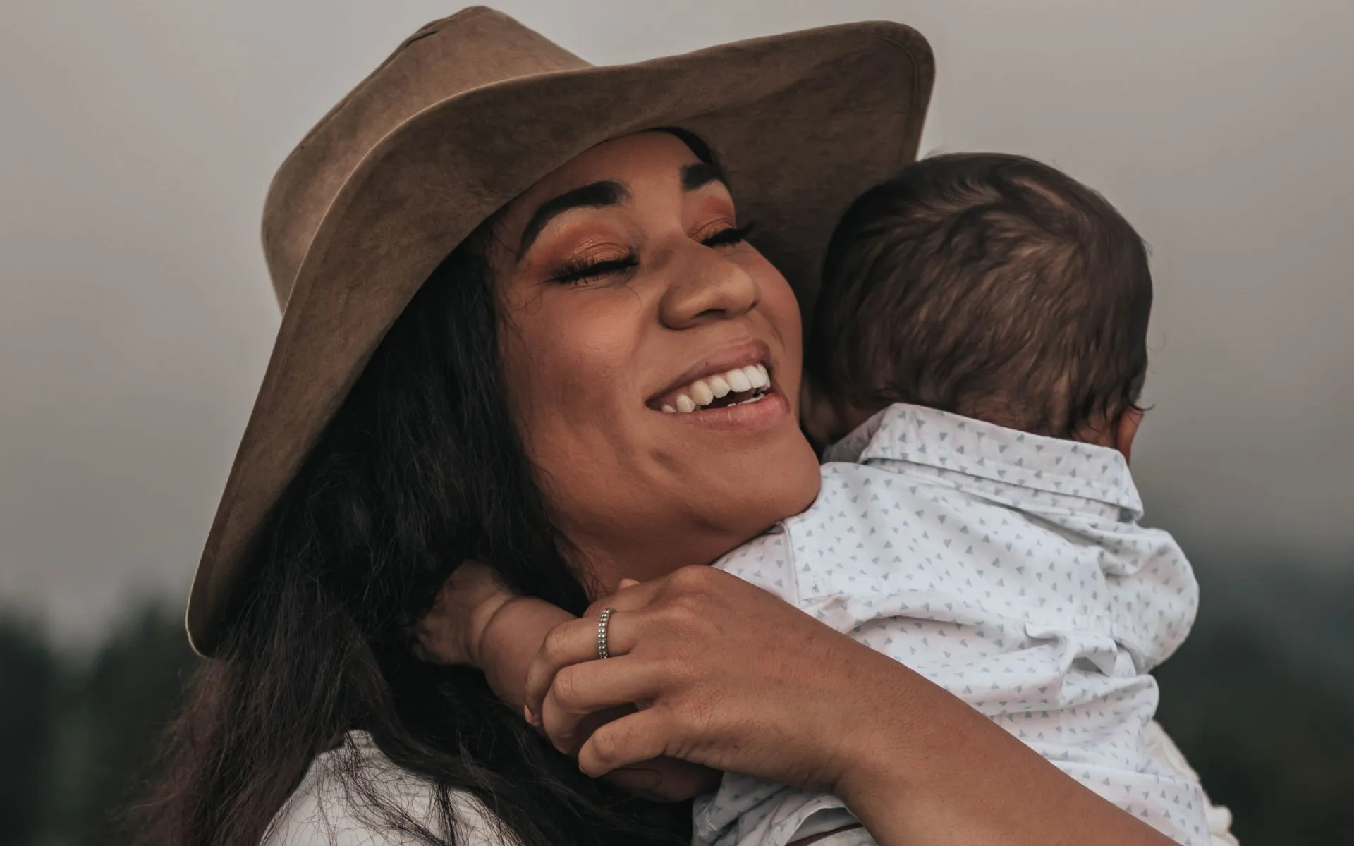 A mother smiles as she holds her baby on her chest. 