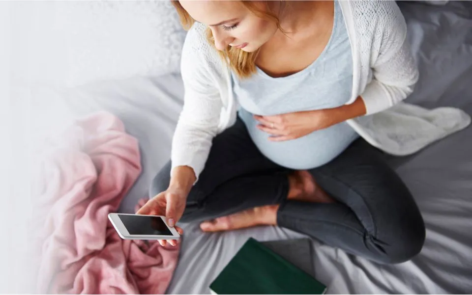 parents kiss their newborn while laying on a bed together