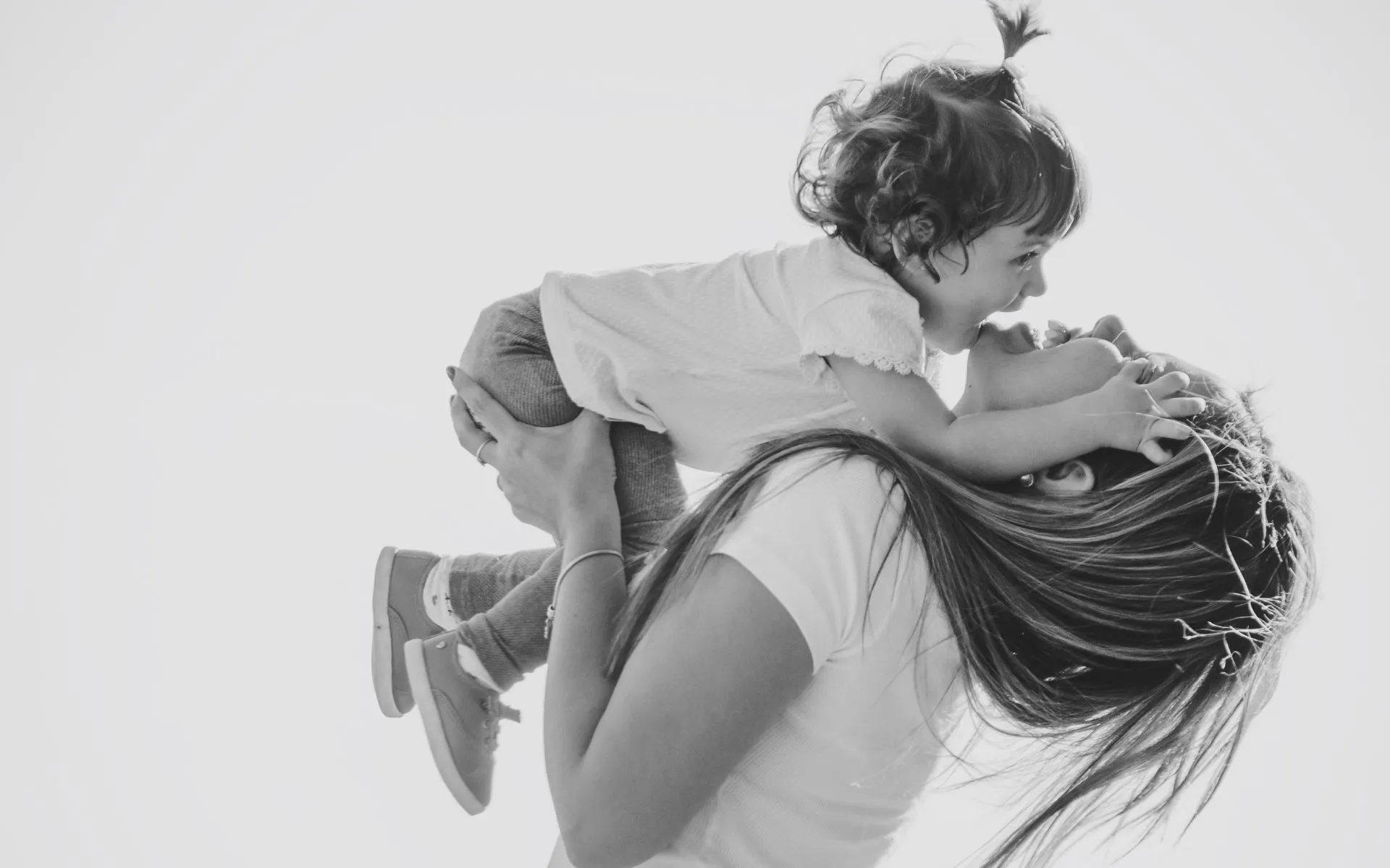 parents kiss their newborn while laying on a bed together