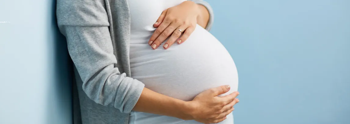 A pregnant woman holds her stomach lovingly, highlighting her pregnancy with a calm and joyful demeanor.