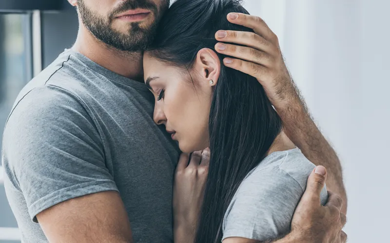 Partner comforts mother who is somber. 