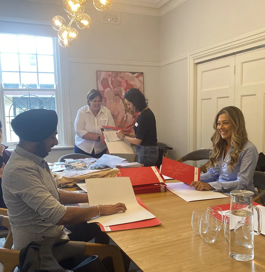 A group of volunteers seated at a table inside Gidget House, sharing ideas and working together on a project.