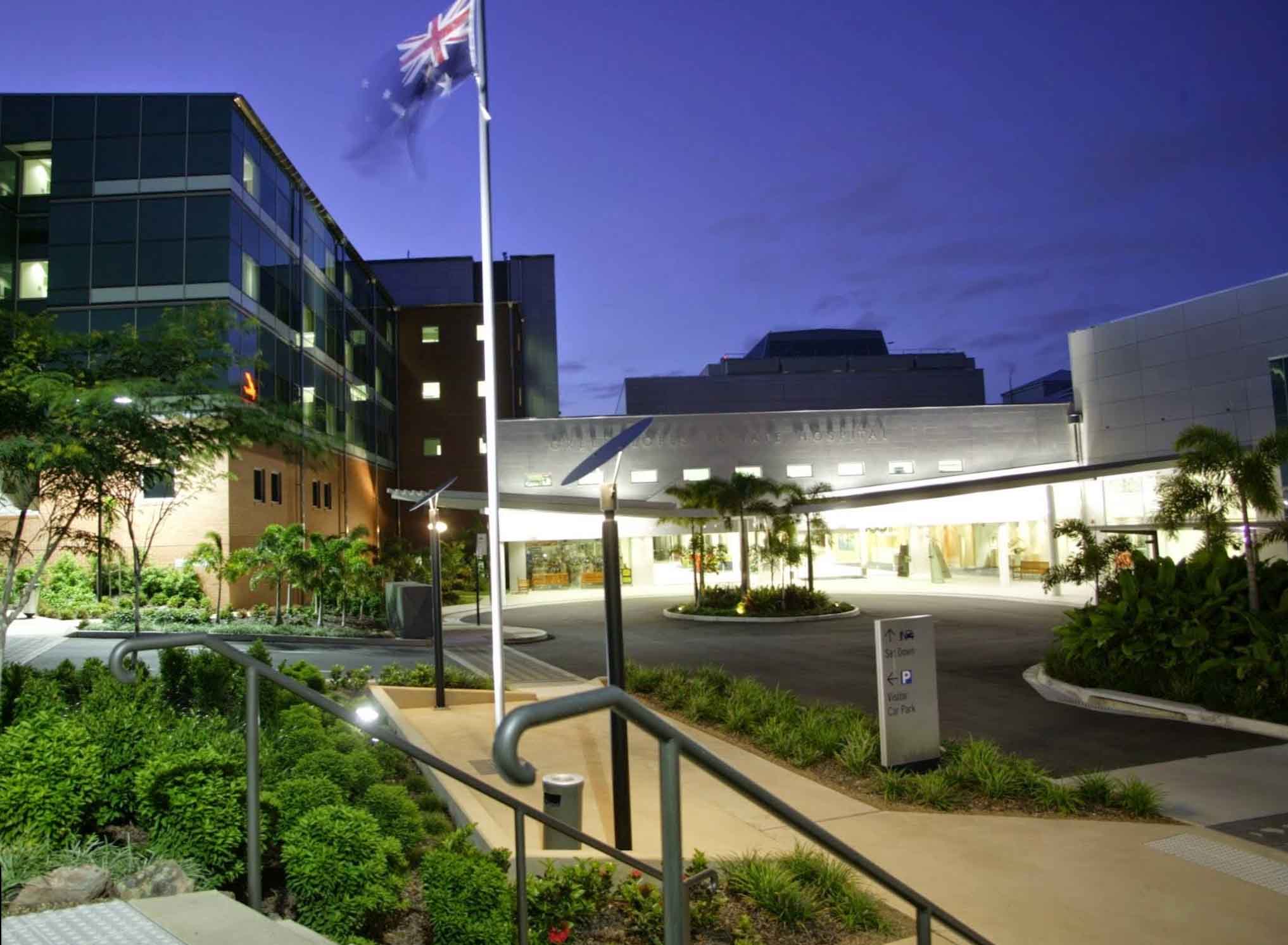 A hospital illuminated at night, with a flag waving gently in the background against a dark sky.