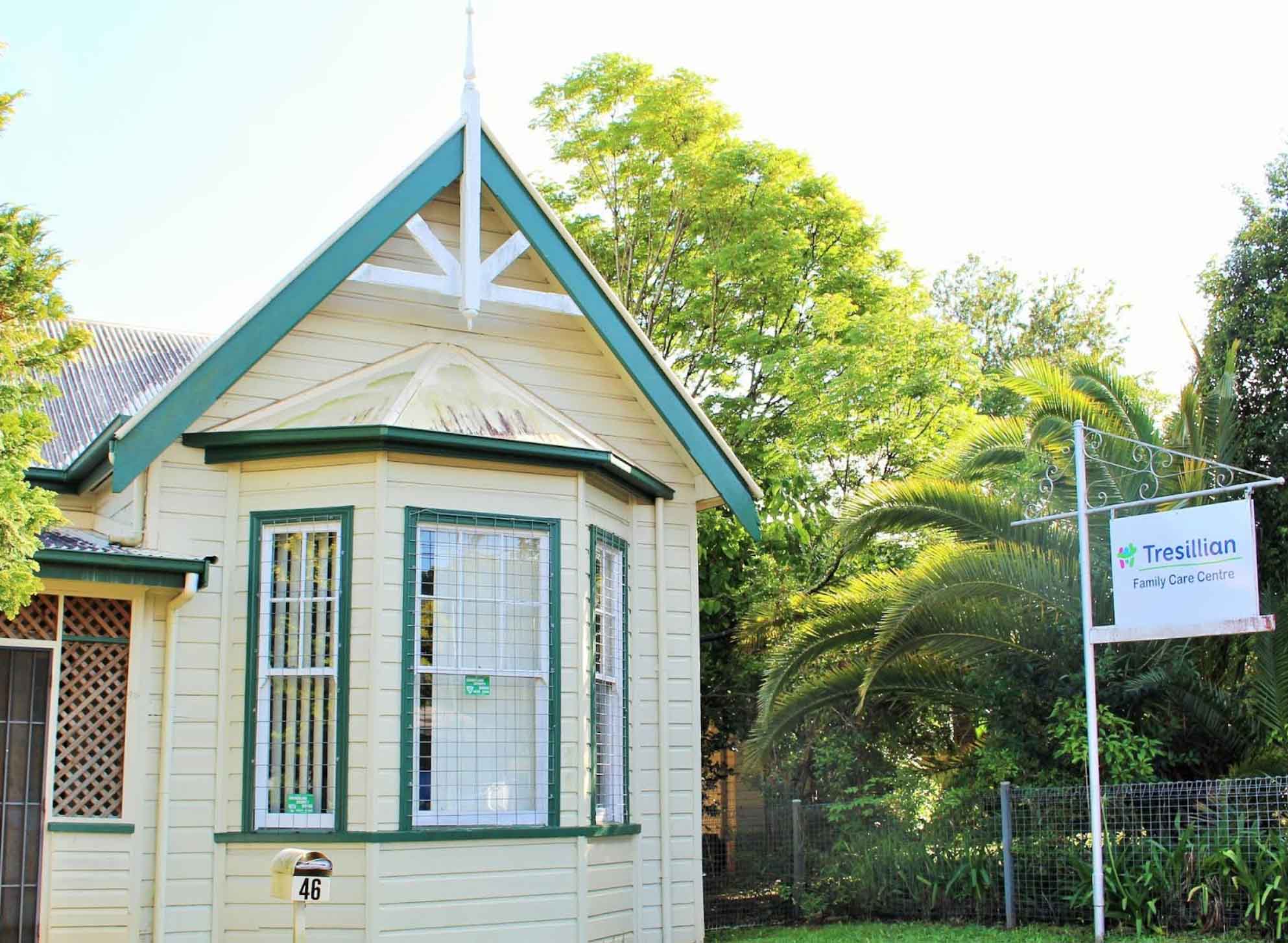 A quaint house with green trim and a Tresillian sign displayed prominently in the front yard.