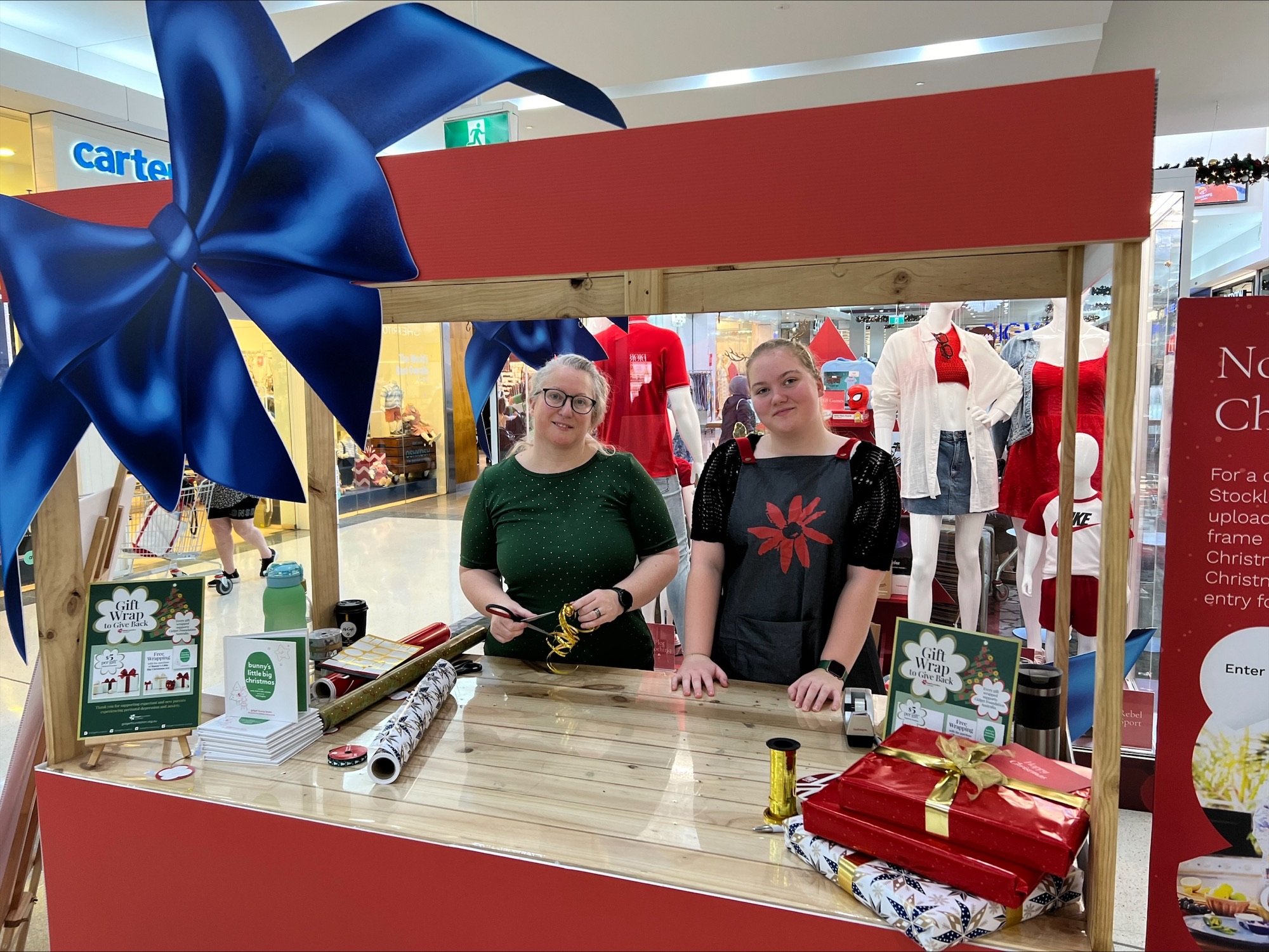 People standing behind Christmas girft wrapping stall