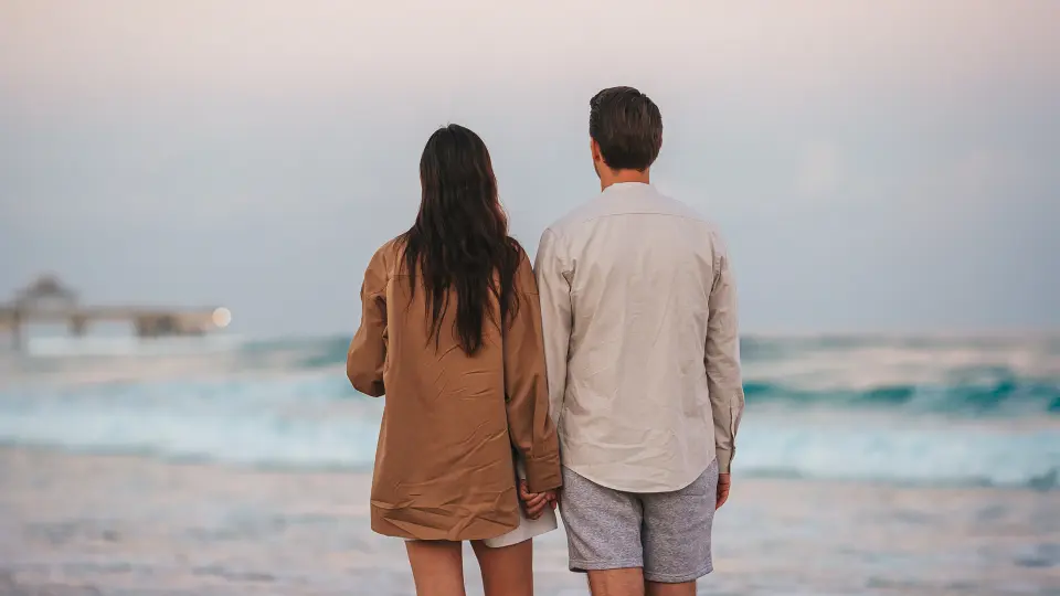 Couple walks on a beach hand in hand.