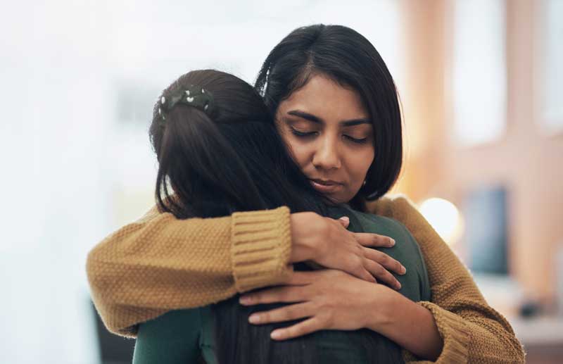 Woman hugs her friend supportively. 