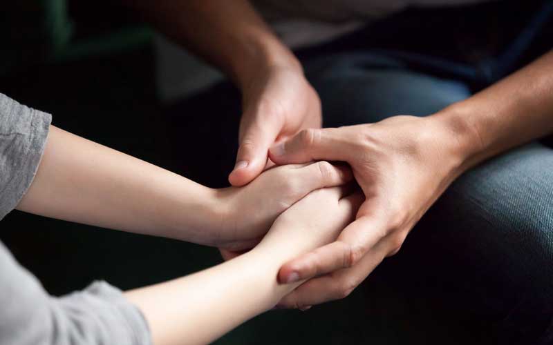 Image of a parents hands being held betweeen another pair. 