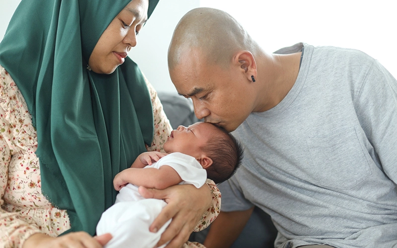  A happy Arabic couple cradling their baby, showcasing a tender family moment.