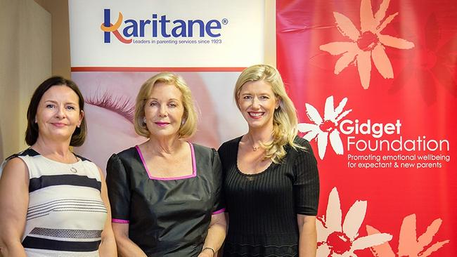 Three women standing indoors with Karitane and Gidget Foundation banners behind them.