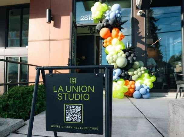 La Union Studio sandwich board sign beside a colorful balloon garland at the building entrance