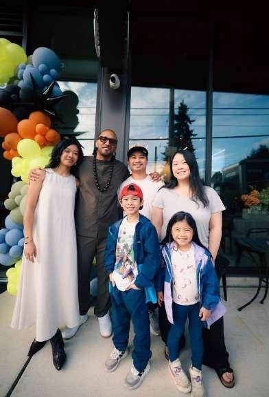 Family of six posing together outdoors in front of the balloon-decorated entrance