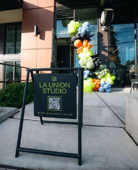 La Union Studio sandwich board sign beside a colorful balloon garland at the building entrance