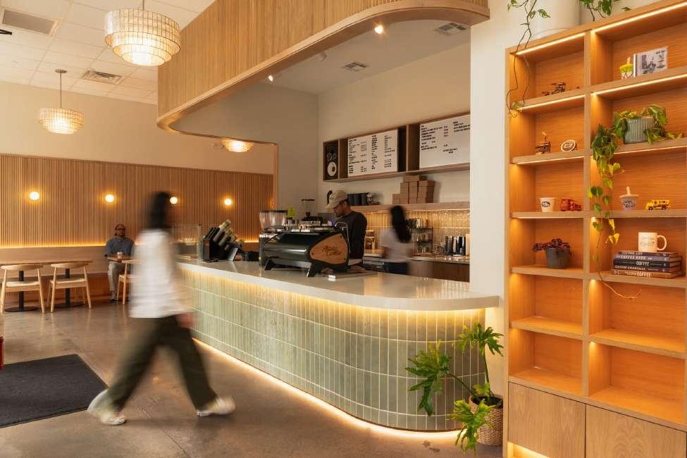 Ayala Coffee counter and wood-paneled display shelves styled with plants, books, and decor