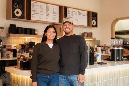 Two Ayala Coffee staff members smiling together behind the counter