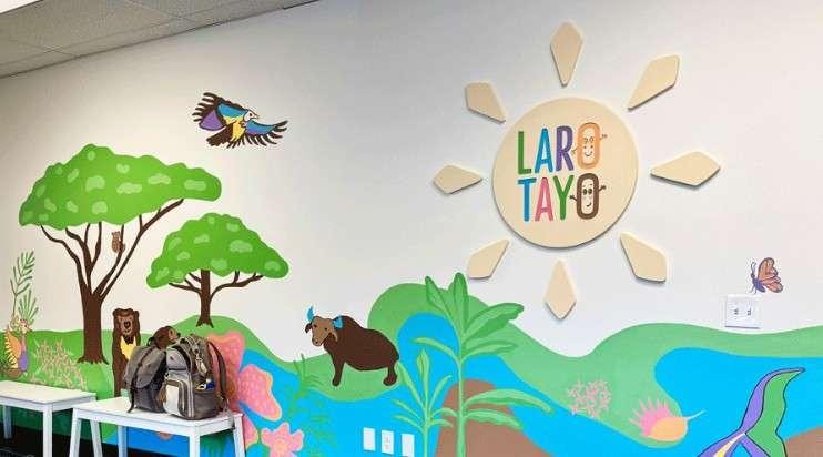Colorful hand-painted mural at Laro Tayo featuring a sun, trees, birds, and a carabao, with the 'Laro Tayo' logo in the center