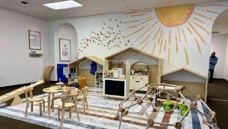 Wooden playhouse and activity area beneath a sun mural inside Laro Tayo