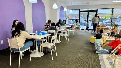 Families and children gathered at tables in a purple-accented room at Laro Tayo