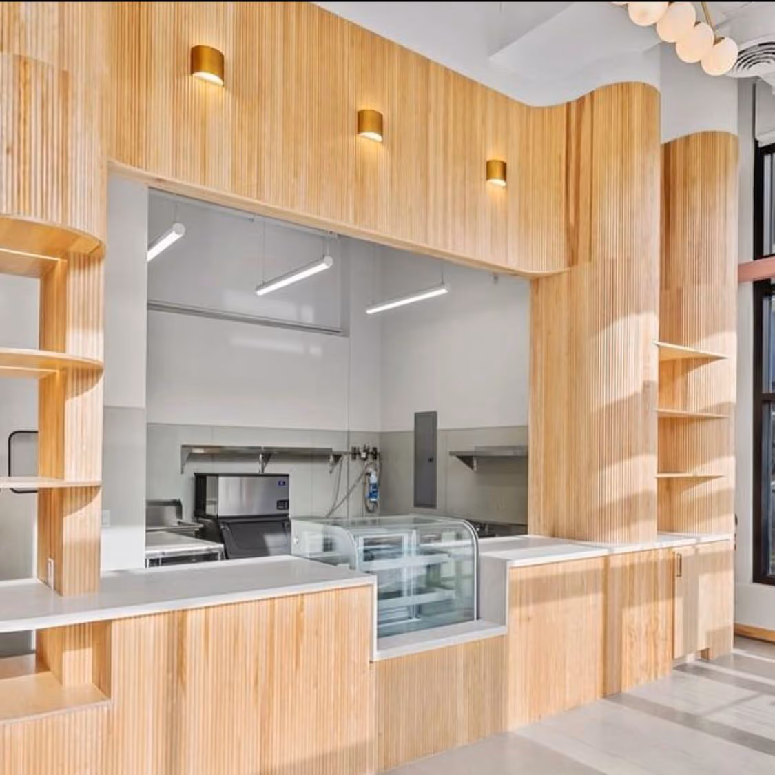 Wood-paneled cafe interior under construction with built-in shelving and a service counter